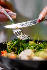 Wall Mural - Person preparing a vibrant, fresh salad, mixing ingredients with a fork and knife. A moment of healthy meal preparation captured