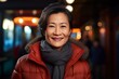 Portrait of a grinning asian woman in her 50s wearing a thermal fleece pullover in front of lively nightclub background