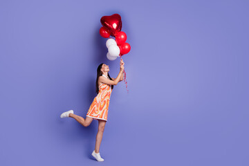 Sticker - Full size photo of pretty young woman hold balloons empty space wear dress isolated on violet color background