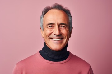 Wall Mural - Portrait of a smiling man in his 60s wearing a classic turtleneck sweater on pastel or soft colors background