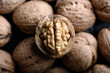 Cracked walnut with kernels on heap of whole walnuts close up. Food photography