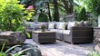 A serene and charming garden patio setting complete with cozy outdoor furniture and accent pillows, creating a relaxing ambiance