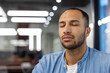 © Tetiana - Close-up photo of young hispanic man sitting at workplace in office with closed eyes and resting