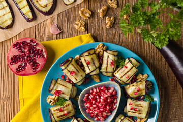 Wall Mural - Delicious appetizer of grilled eggplants. Wrapped in rolls with nut paste. Served with pomegranates.