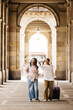 © Jordi Salas - Two young cheerful women pulling a suitcase and walking together through a city during a weekend trip.