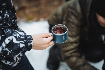 Wall Mural - A mug of tea in hand, a brown clear drink in a glass, camping in nature, a hedgehog on a hike, trekking in the mountains, hiking in the forest.