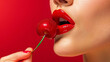 Woman eating cherry close up of lips with glossy red lipstick on red background. Colorful banner for fashion beauty makeup concept