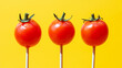 Three cherry tomatoes lollipops on bright yellow background. Healthy diet diabetes prevention sugar cravings concept