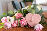 Fototapeta Kosmos - Bouquet of pink roses with ranunculus and pink heart shape on wooden table for mother's day greetings.