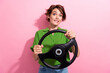 Photo portrait of attractive young woman nervous driver hold steering wheel wear trendy green clothes isolated on pink color background