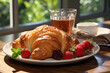 Croissant with berries and cup of coffee on the table in moderm kitchen, window on background.