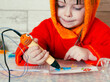 Children's hands make a craft using a 3D printing pen. A girl draws with a 3D pen.