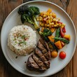 Plate with steak, rice and vegetables on table