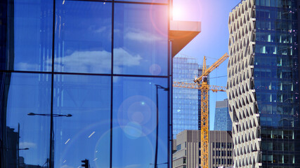 Wall Mural - Glass building with transparent facade of the building and blue sky. Structural glass wall reflecting blue sky. Abstract modern architecture fragment. Contemporary architectural background.