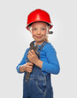 Little girl worker in a safety helmet with a tool on a light background.