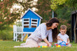 Mother and toddler boy playing in the park while having picnic