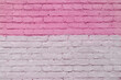 The texture of an old brick wall is painted with white and pink paint.