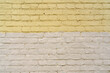 The texture of an old brick wall is painted with white and yellow paint.