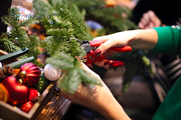 Family making christmas wreath from fir branches, christmas balls and pine cones on the wooden table