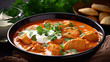Chicken tikka masala in tomato sauce with sour cream and parsley on black background