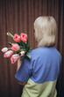 a woman holding a bouquet of tulips with a blue shirt on
