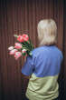 a woman holding a bouquet of tulips with a blue shirt on