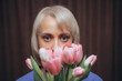 a woman with blonde hair and a blue shirt is holding a bunch of tulips