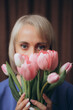 a woman with blonde hair and a blue shirt is holding a bunch of tulips