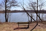 Fototapeta Niebo - The empty bench on the shore at the lake.