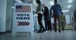 © Framestock - Vote here sign on the floor. Multi ethnic American citizens vote in booths in polling station office. National Election Day in United States. Political races of US presidential candidates. Civic duty.