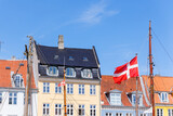 Fototapeta Natura - Danish flag waves background Nyhavn colorful house buildings in canal harbor Copenhagen sightseeing tourist travel destination in Denmark on sunny day. Clear blue sky backdrop