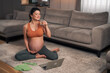 A satisfied pregnant woman drinking water and taking a break after her yoga session at home
