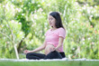Asian pregnant woman meditating while sitting in a lotus position in the park, Meditating on maternity