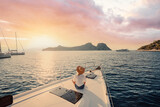 Fototapeta Morze - Luxury travel on the yacht. Young woman on boat deck sailing the sea. Yachting on sunset