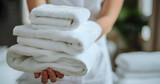 Fototapeta Londyn - Close up hand of a professional chambermaid putting stack of fresh towels in hotel room.
