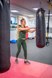 Young woman stands next to a black boxing pear to let off steam in gym