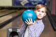 Cute kid boy teenager with ball at bowling club