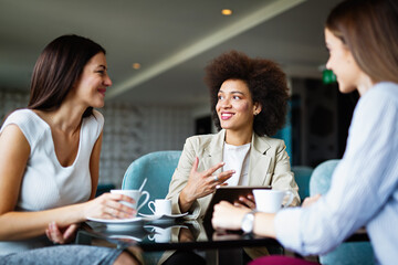 Sticker - Business woman and her clients discuss business ideas and collaborate over coffee in a cafe.