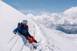 Woman snowboarder resting on slope of powdery snow in high mountains avalanche-prone area. Freeride at ski resort, Snow splashes trail,  mountain peaks view