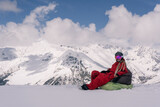 Fototapeta  - Woman freerider snowboarder sitting on the slope relaxing while skiing off piste