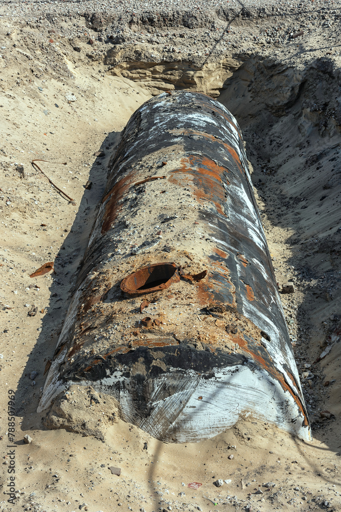 excavated weathered underground storage tank lies outside in the sand