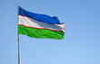 Flying Uzbek flag or Flag of Uzbekistan against blue sky..