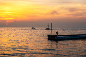 Wall Mural - Sunset on the sea with boats and people on the pier