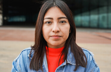 Portrait of native american woman looking on camera with city in background - Indigenous girl outdoor