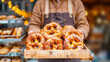Vendor clad in apron presents a wooden tray brimming with traditional German pretzels, dusted with sugar, invoking the cozy ambiance of festive market. Street food. Bakery shop