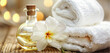 White folded terry cloth towels frangipani flowers massage oil in glass on wood table. Candle lights. Spa wellness relaxation body and skin care concept