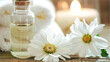 White folded terry cloth towels chamomile flowers massage oil in glass on wood table. Candle lights. Spa wellness relaxation body and skin care concept