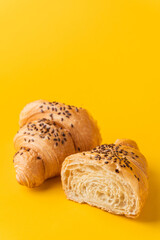 Wall Mural - Macro shot of fresh croissant cut in a half on the yellow background. Copy space for a free text