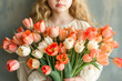 A portrait of a young girl holding a bouquet of orange tulips. Greetings of mother's day.