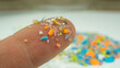 Macro shot of microplastics on the tip of a finger. Concept of plastic pollution with nanoplastics. Soft focus on a micro plastic particles that cannot be recycled with copy space on the right.